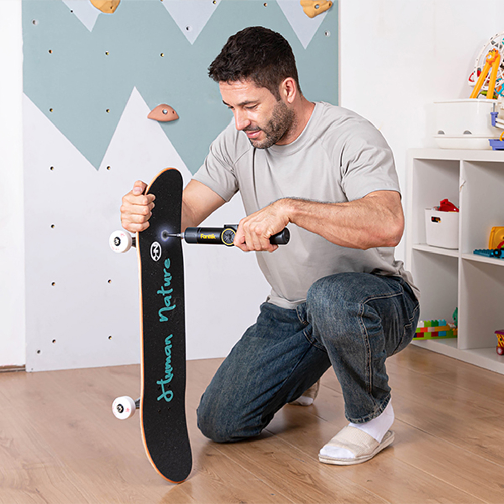 Mężczyzna przykręcający montażówki deskorolki wkrętakiem  Fold S1 APEX