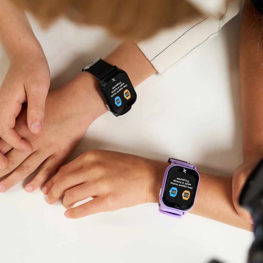 Widok z góry na dziecięce ręce ze smartwatchami FW49 na nadgarstkach - na obu uruchomiona funkcja 'Przyjaciele' - zbliżenie.