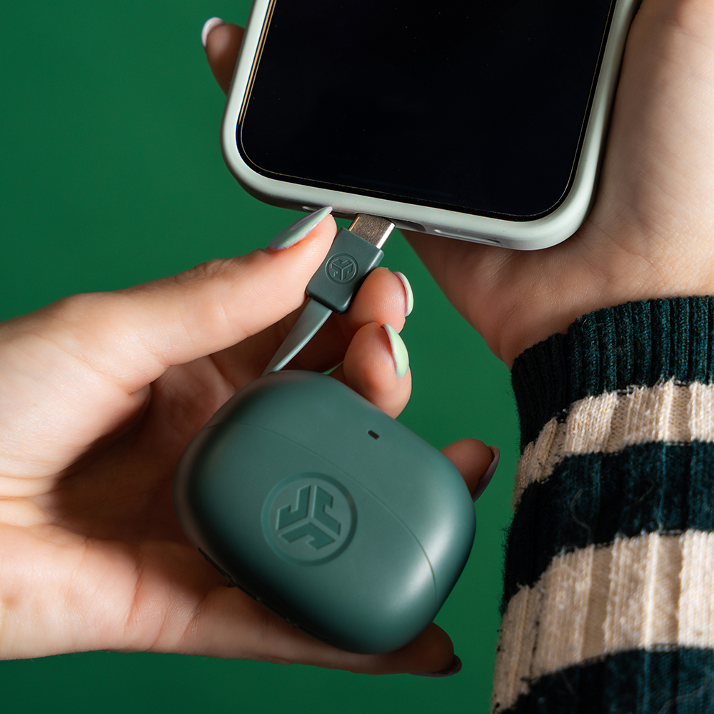 Zbliżenie na kobiecą dłoń podpinającą etui słuchawek JLab Go Pods ANC do wejścia ładowania smartfonu.