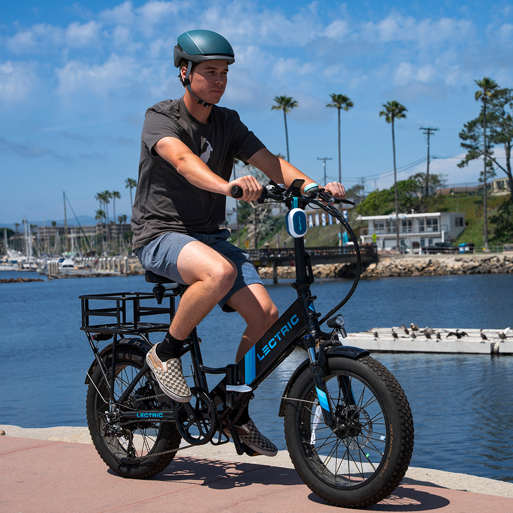 Mężczyzna na rowerze elektrycznym z przypiętym głośnikiem JLab Pop Party.