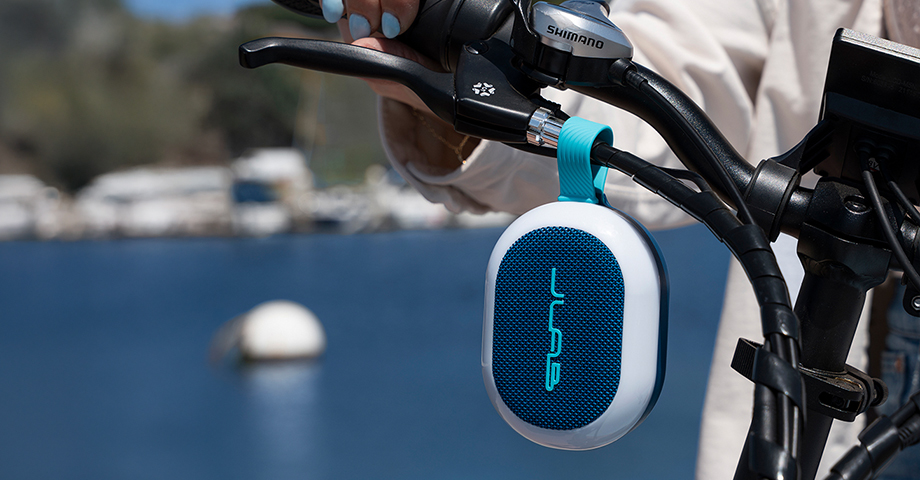 Głośnik JLab Pop Party zawieszony na kierownicy roweru.