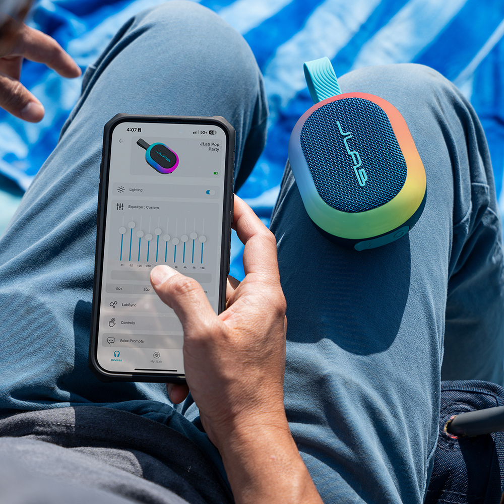 Mężczyzna zmieniający ustawienia głośnika JLab Pop Party przy pomocy aplikacji mobilnej.