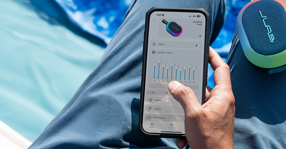 Mężczyzna zmieniający ustawienia głośnika JLab Pop Party przy pomocy aplikacji mobilnej.