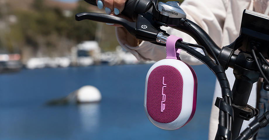 Głośnik JLab Pop Party zawieszony na kierownicy roweru.