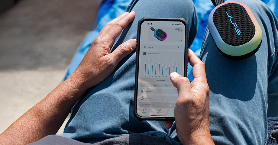 Mężczyzna zmieniający ustawienia głośnika JLab Pop Party przy pomocy aplikacji mobilnej.