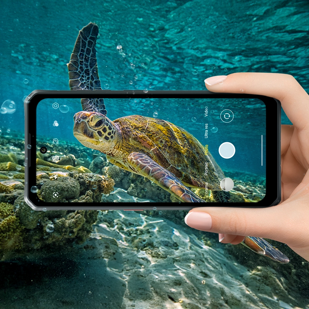 Zbliżenie na dłoń robiącą zdjęcie żółwiowi morskiemu pod wodą przy pomocy Fossibota F114.