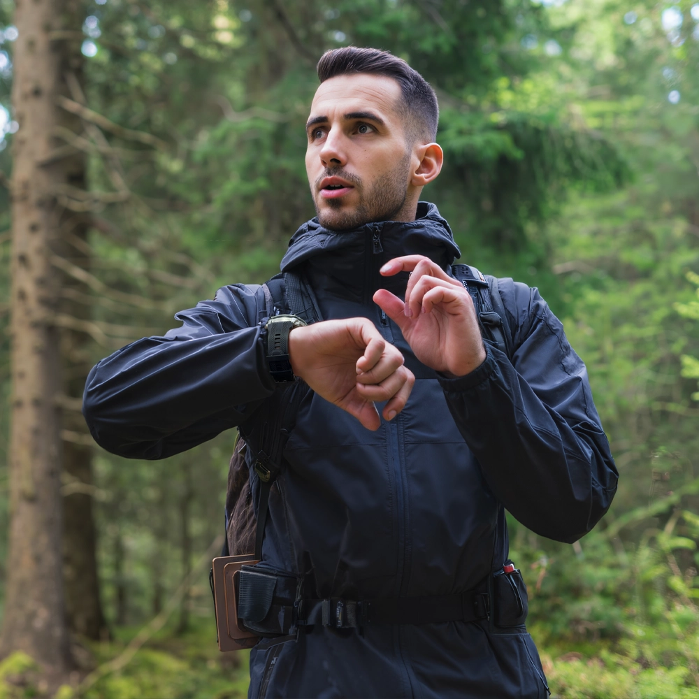 Zbliżenie na mężczyznę w lesie korzystającego ze smartwatcha Kospet Tank T4, który ma na nadgarstku.